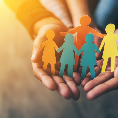 Children and adults holding a paper cutout of a family, a home, an adoption foster care program, a homeless charity, a household budget during inflation