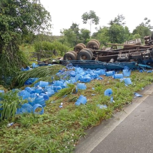Caminhão tomba na BR-364 e espalha carga de galões de água